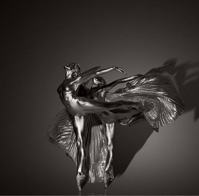 Touching the earth and reaching to the sky, silver dancers flying with wings by guido Argentini, two dancers in arabesque with pleated fabric