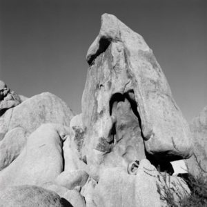 The bending on a stone by Guido Argentini, nude model crouching between giant rocks