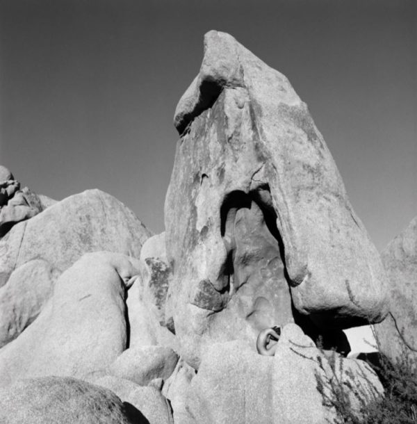 The bending on a stone by Guido Argentini, nude model crouching between giant rocks