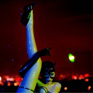 Thea as a cat by guido Argentini, model in latex dessous, illuminated in green and blue lights in front of red city lights