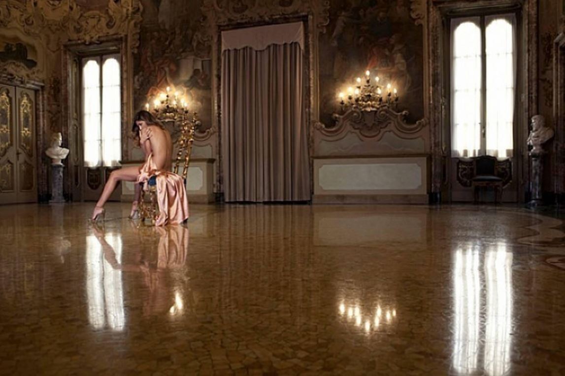 Until eternity comes by Guido Argentini, model in peach gown sitting on a gold chair in baroque interior