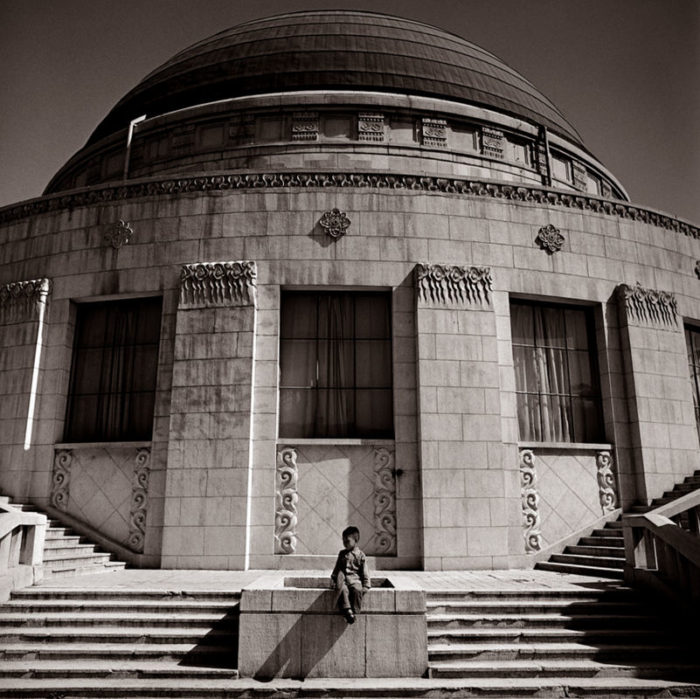 Boy awaiting Parents - Beijing Observatory 1979 by Albert Watson, by sitting on a staircase in front of a round dome building