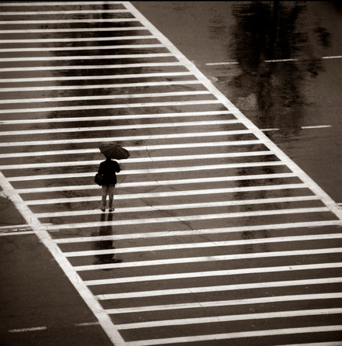 Crosswalk - Beijing Hilton 1979 by albert watson, a single person with an umbrella on a crosswalk