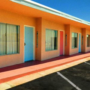 Glass Pool Inn - Las Vegas 2001 by albert watson, orange single storage building with parking lot under blue sky