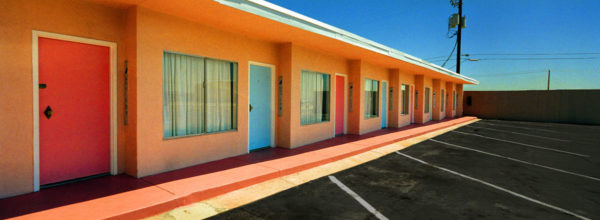 Glass Pool Inn - Las Vegas 2001 by albert watson, orange single storage building with parking lot under blue sky