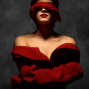 Los Angeles 1989 by ALbert Watson, portrait of model in red offshoulder coat and red fabric covering her eyes, while she wraps her arms around herself