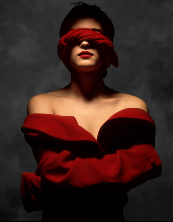 Los Angeles 1989 by ALbert Watson, portrait of model in red offshoulder coat and red fabric covering her eyes, while she wraps her arms around herself