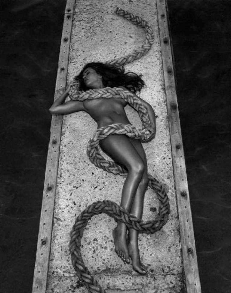 Iveta - Lesbos by Andreas H. Bitesnich, model lying on a jetty with a rope wrapped around and covering her nude body
