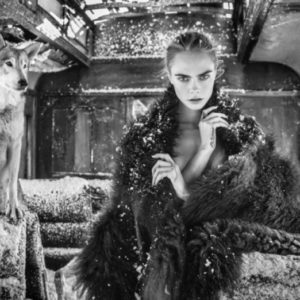 The Girl on Train by David Yarrow, nude model covered in fur in a broken train with snow, next to a wolf