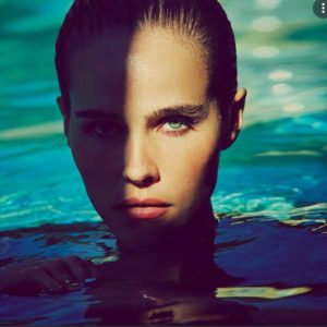Deep End by Guy Aroch, Model with green eyes sticking her head out of blue and green water, partially covered in shadow