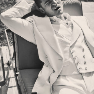 Orlando Bloom by Guy Aroch, the actor in a white suit lounging on a