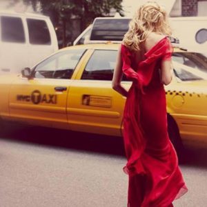Taxi by Guy Aroch, model in red gown crossing the street between yellow taxis
