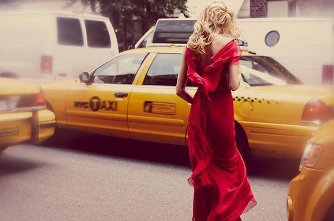 Taxi by Guy Aroch, model in red gown crossing the street between yellow taxis