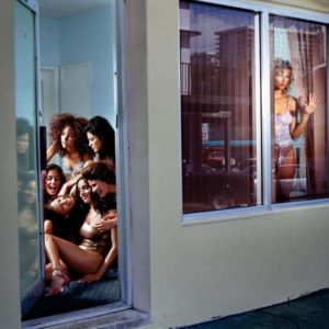 Gina and the rivals by David Drebin, model in purple lingery looking out of a mirror while a group of models is sitting nextdors