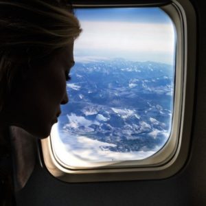 Higher Love by David drebin, model looking out of aircraft window at snowy mountains