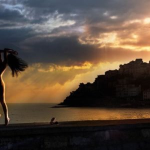 Mediterranean dream by David Drebin, nude model jumping on the beach in front of porto maurizio in the sunset