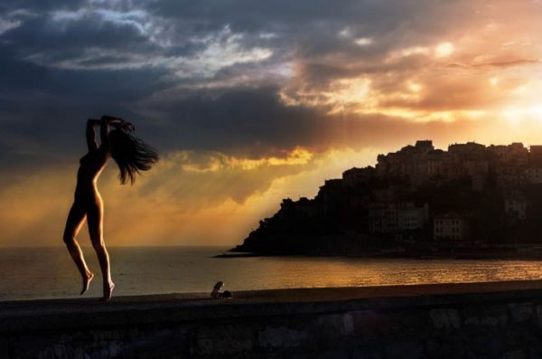 Mediterranean dream by David Drebin, nude model jumping on the beach in front of porto maurizio in the sunset