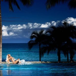Splasher in paradise by David Drebin, nude model sitting on a beach between palm trees, splashing in the water
