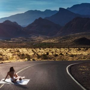 The road warrior by Drebin, model in white bathing suit sitting on a road in the outback
