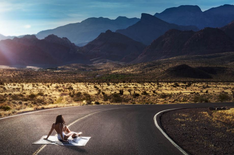 The road warrior by Drebin, model in white bathing suit sitting on a road in the outback