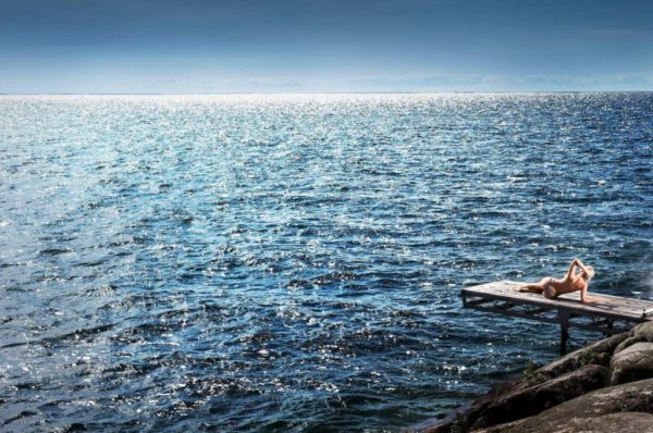 Kissing the sky by David Drebin, nude model lying on boat jetty over the ocean