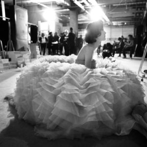 Dior Haute Couture by Gérard Uféras, model in big ruffle dress sitting on the floor backstage