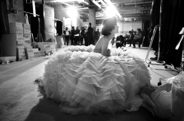 Dior Haute Couture by Gérard Uféras, model in big ruffle dress sitting on the floor backstage