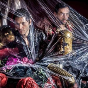 Aaron I by Iris Brosch, two male models in gold armour with fabric flowers underneath a transparent plastic wrap
