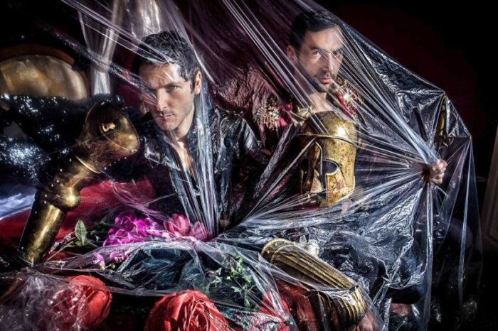 Aaron I by Iris Brosch, two male models in gold armour with fabric flowers underneath a transparent plastic wrap