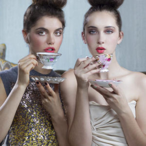 Untitled V by Iris Brosch, two models with high topknots and pink lips drinking from antique teacups with flower decor