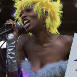 Junglepussy by Marc Baptiste, portrait of the rapper wearing yellow heair and a feather bustier performing at the 2019 afropunk festival