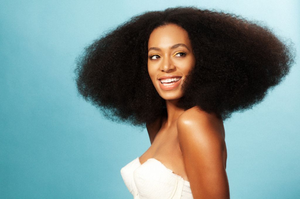 Solange Knowles by Marc Baptiste, portrait of the singer wearing her afro and a white bustier, in front of a turquoise background