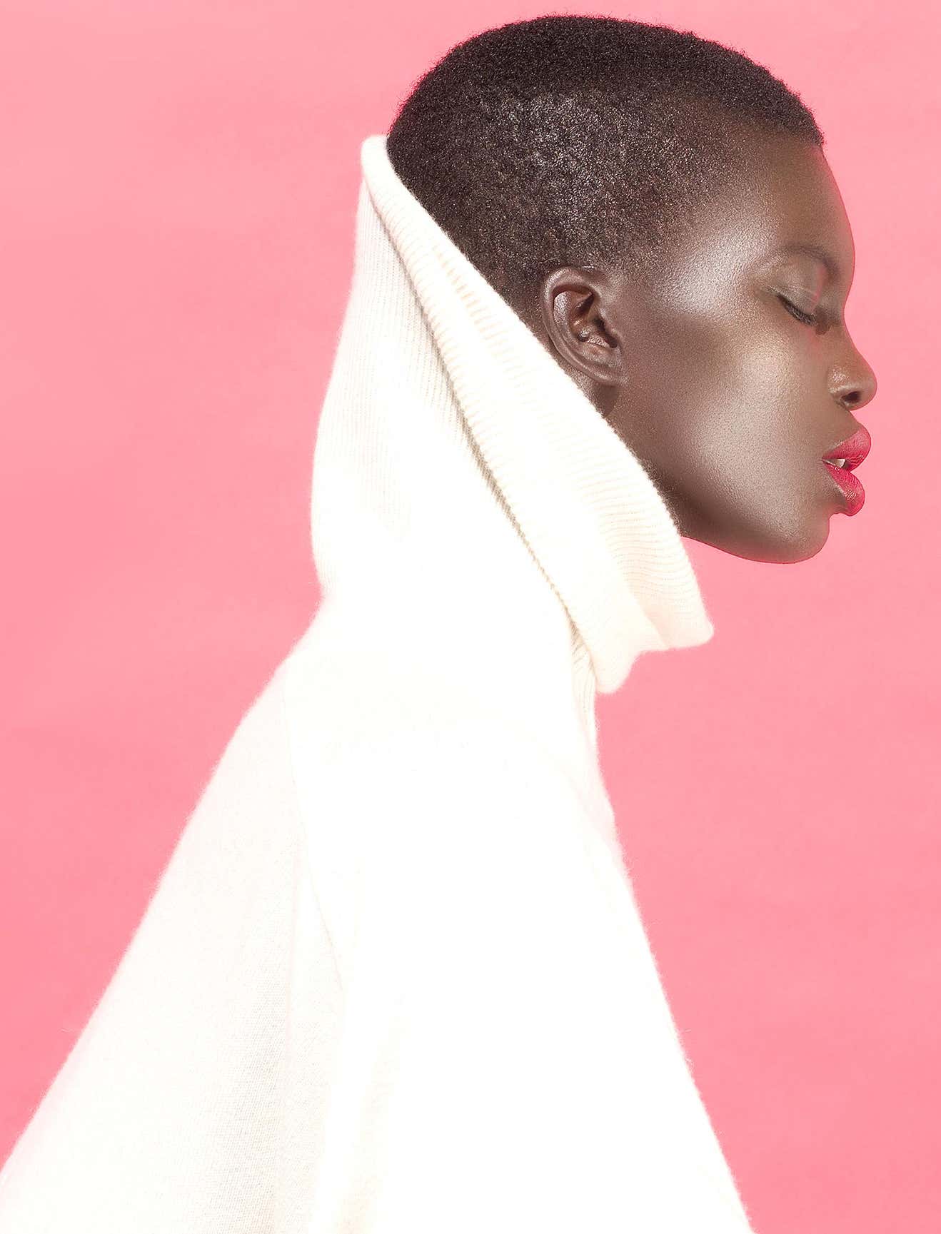 Ashock by Sylvie Blum, sideprofile of a black model in a white turtleneck and red lip with pink background