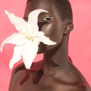 Flower Two by Sylvie Blum, black model with turquoise eyeliner and a white Lily in her mouth
