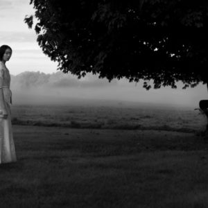 Gemma Khan by Sylvie Blum, model in white dress standing on a foggy meadow surrounded by trees, b&w