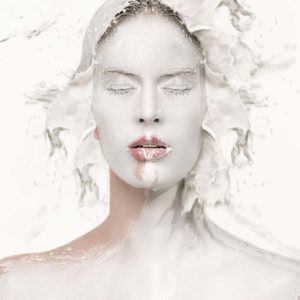 Milk One by Sylvie Blum, portrait of model with white painted face, white liquid splashing around her head