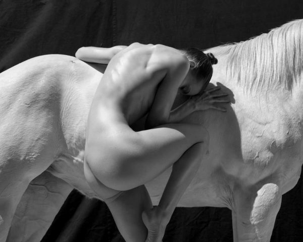 Palms Spring Two by Sylvie Blum, nude model bending next to a white horse, in balck and white