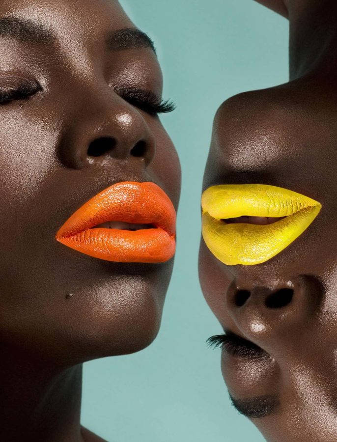 Pop Lips One 201 by Sylvie Blum, closeup of two black models with bright roange and yellow lips, one of them upside down