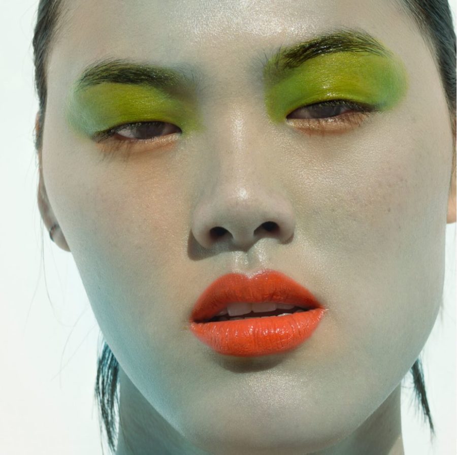 Pretty peaushun skincare cocoshica by Sylvie Blum, closeup portrait of model with her face painted light blue, green eyeshadow and orange lips