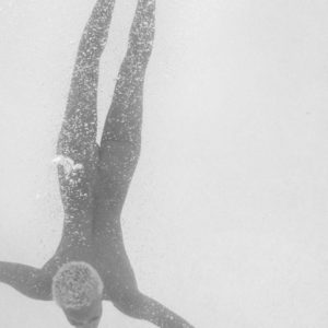 The Dive by Sylvie Blum, model with short hair diving, surrounded by airbubbles