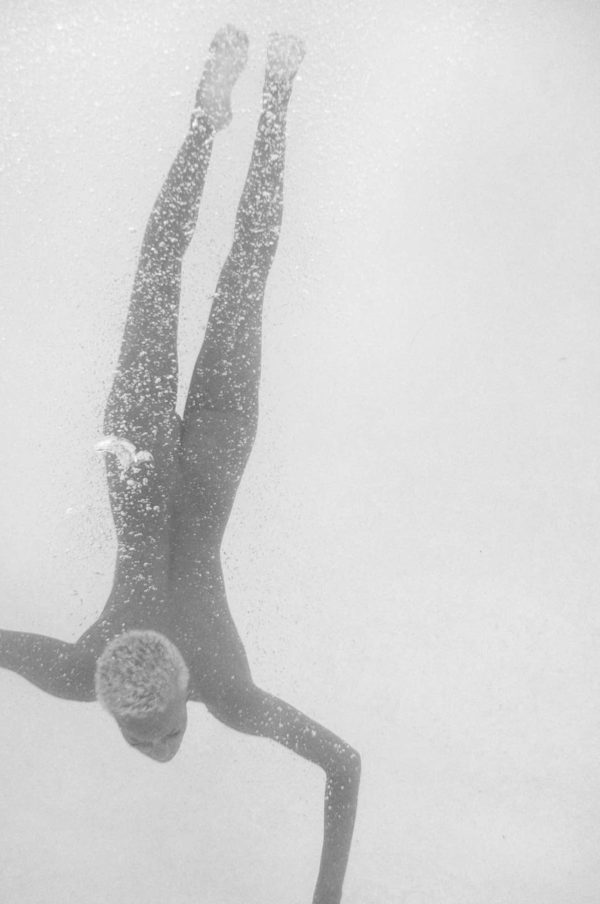 The Dive by Sylvie Blum, model with short hair diving, surrounded by airbubbles