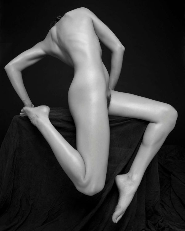 The combination by Sylvie Blum, model with twisted body and bent legs in front of black background