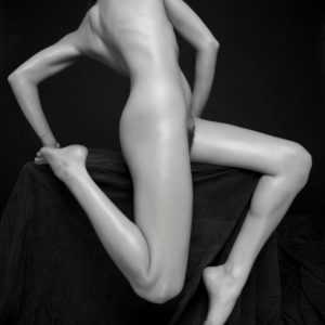 The combination by Sylvie Blum, model with twisted body and bent legs in front of black background