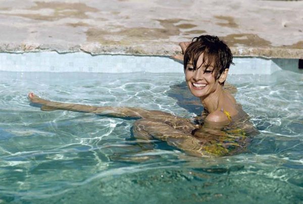Audrey Hepburn in the Pool by Terry O'Neill, the actress in a yellow swimsuit sitting in a pool, smiling