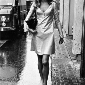 Jean Shrimpton by Terry O'Neill, the model in a short white dress walking through rainy streets barefoot