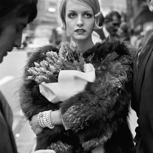 Twiggy with Flowers by Terry O'Neill, the model in a furcoat holding a flower bouquet