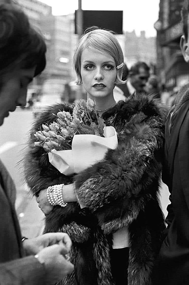Twiggy with Flowers by Terry O'Neill, the model in a furcoat holding a flower bouquet