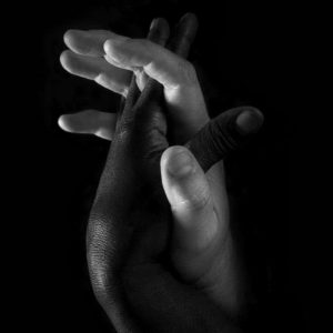 Hands 'One' Black & White by Timothy White, a white and a black hand intertwined