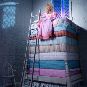 Whoopi Goldberg III by Timothy White, the actress in a pink dress and blonde wig sitting on a stack of colorfull matresses,