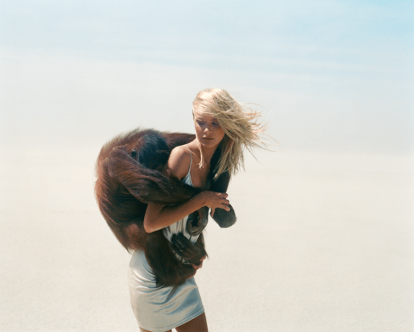 Michel Comte's Beauty and Beast series, model in silver dress carrying a monkey on her back in the desert